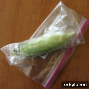 Lock in Flavor: Freezing Corn on the Cob, Husk Included 8 Corn on the cob wrapped in plastic and placed in a freezer bag, air being removed