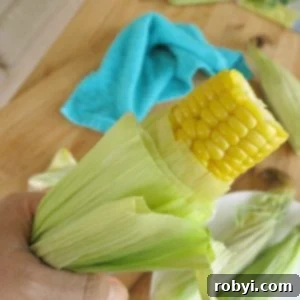 Lock in Flavor: Freezing Corn on the Cob, Husk Included 10 Microwave Corn on the Cob being pulled from husk, illustrating easy removal after cooking