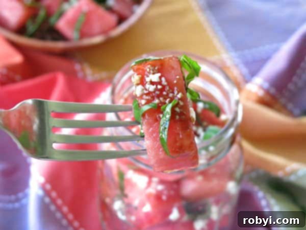 A fork holding a piece of Watermelon Basil Feta Salad, showcasing the ingredients together.