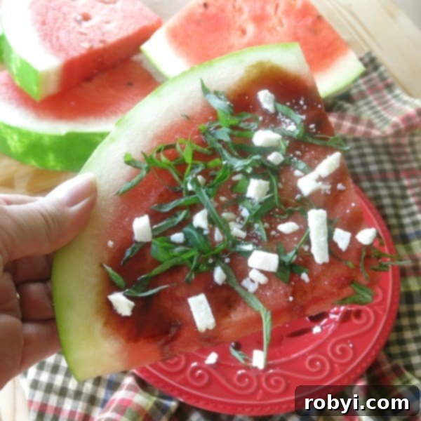 A thick slice of watermelon topped generously with crumbled feta cheese, fresh basil, and a sweet balsamic reduction.