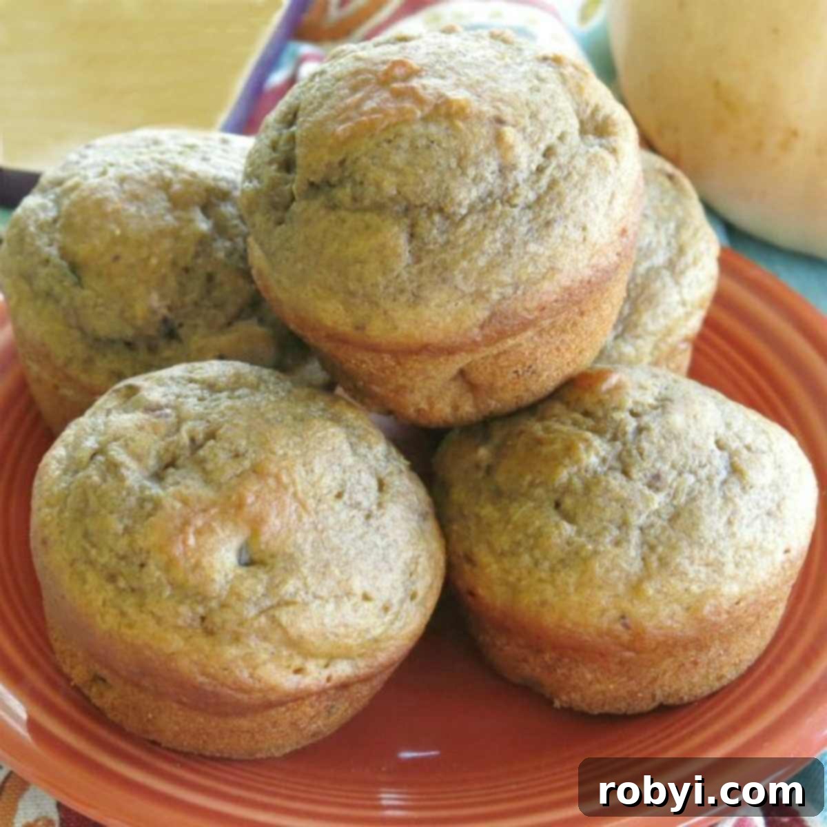 Healthy butternut squash muffins with apple stacked on a plate, garnished with cinnamon and walnuts.