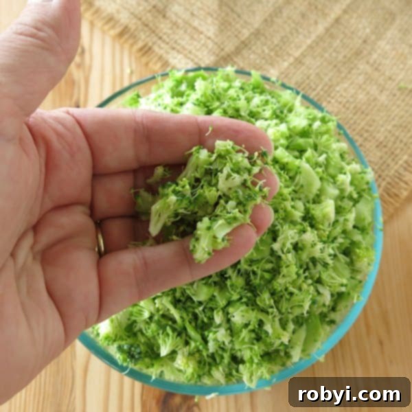 Bowl or riced broccoli with hand holding some of it