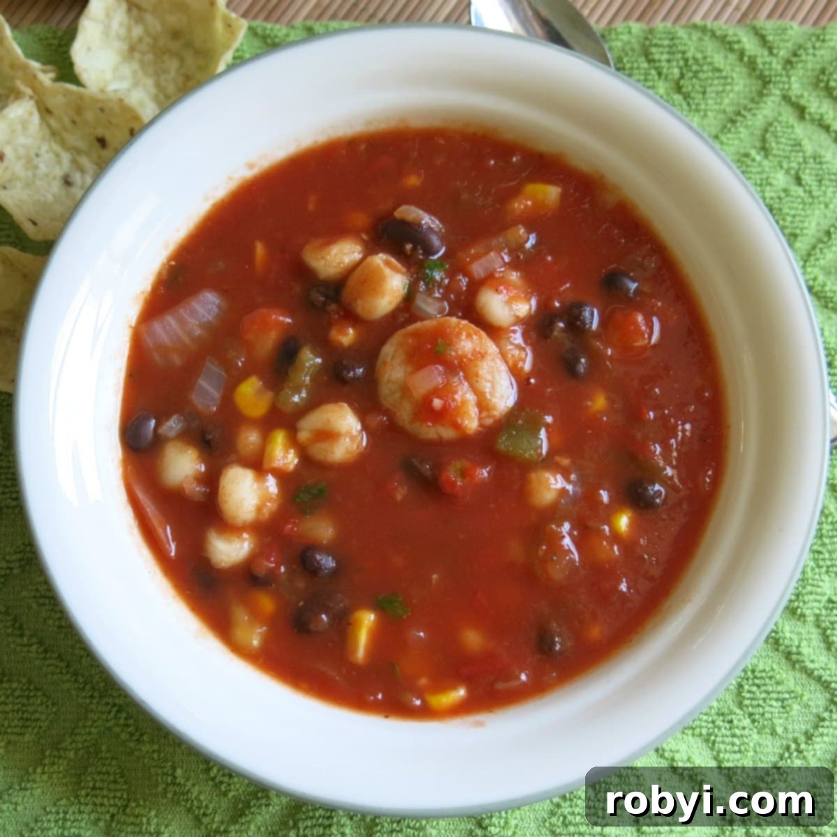 A vibrant bowl of Shrimp Tortilla Soup, garnished with fresh cilantro and a sprinkle of cheese.