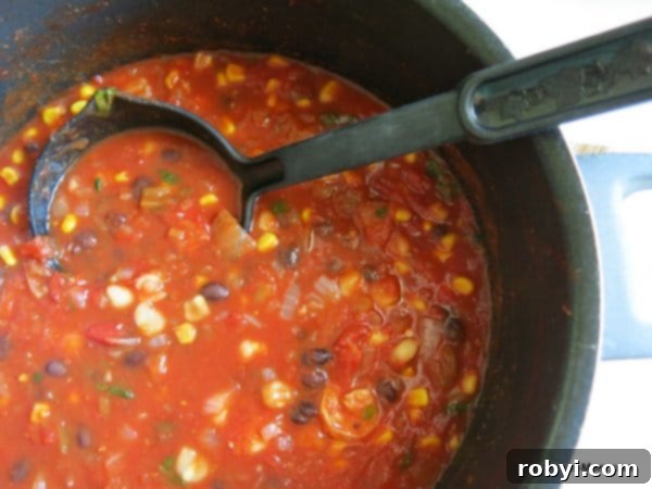 Seafood tortilla soup simmering in a stock pot with a ladle resting inside.