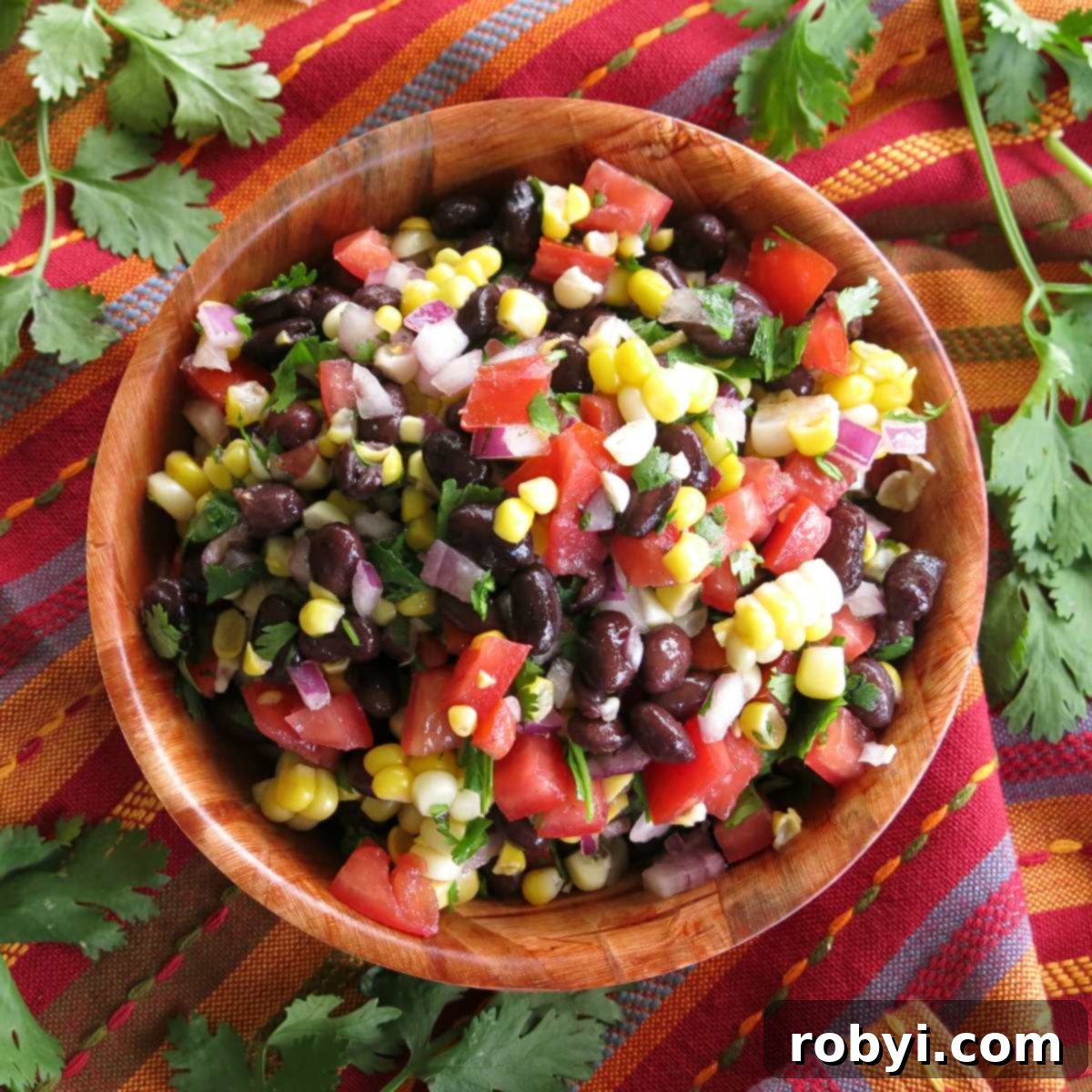 A beautifully presented bowl of fresh corn and black bean salsa, garnished with vibrant red wine vinegar dressing, ready to be enjoyed as a healthy appetizer or side dish.
