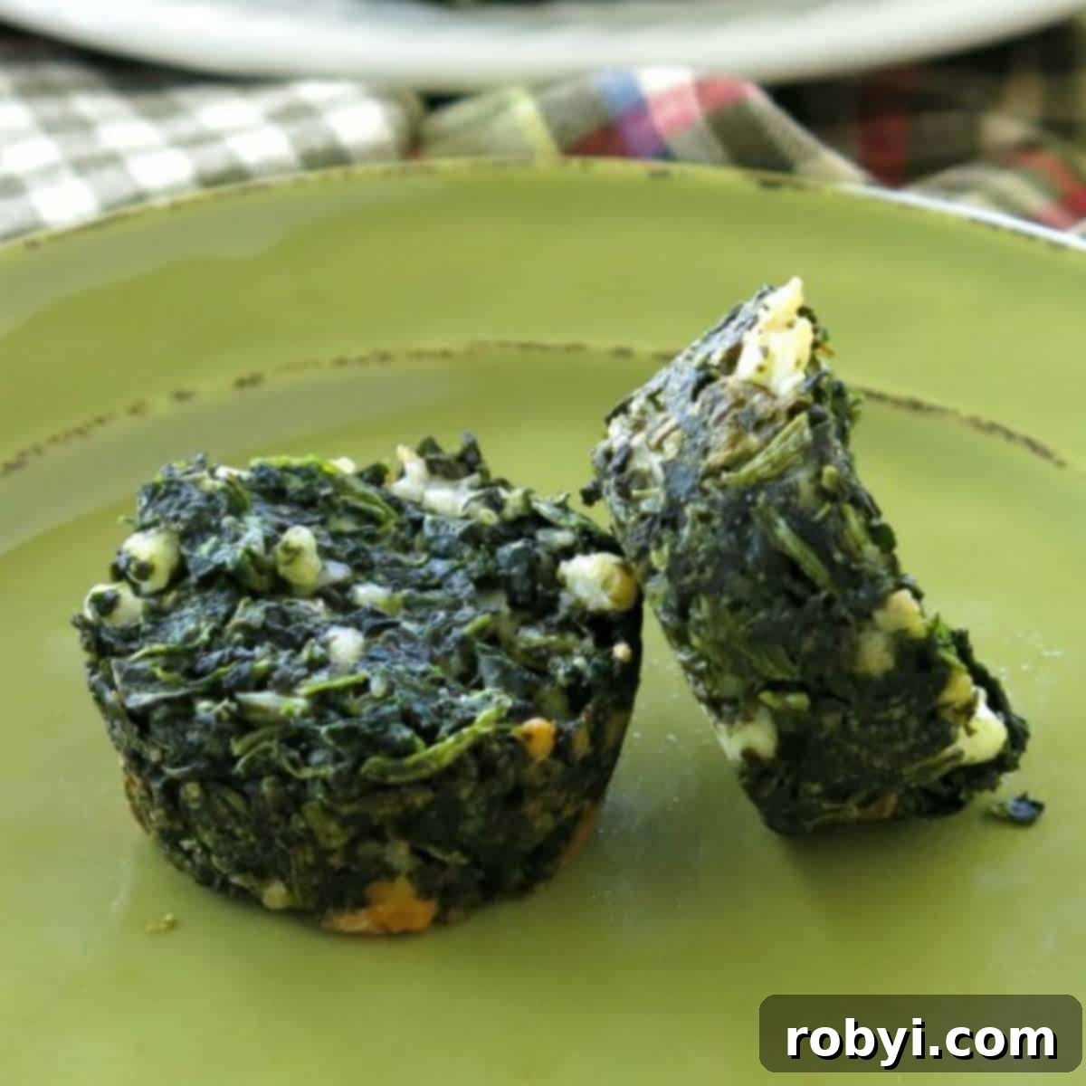 Two vibrant spinach feta egg cups presented beautifully on a minimalist plate, highlighting their golden-brown edges and fluffy texture.