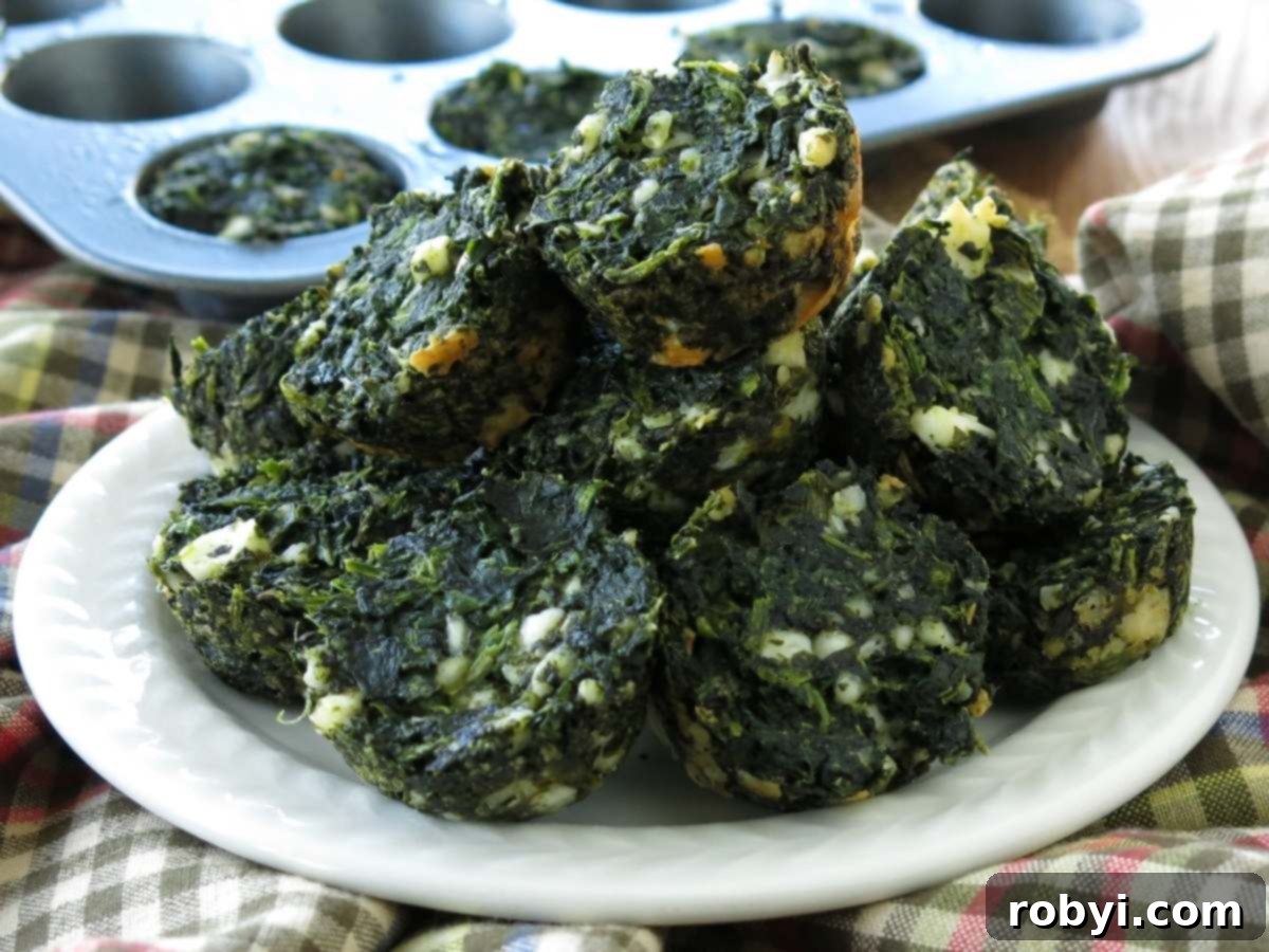 A beautifully arranged plate of golden-brown keto spinach feta egg muffins, with a mini muffin pan visible in the soft-focused background, ready for serving.
