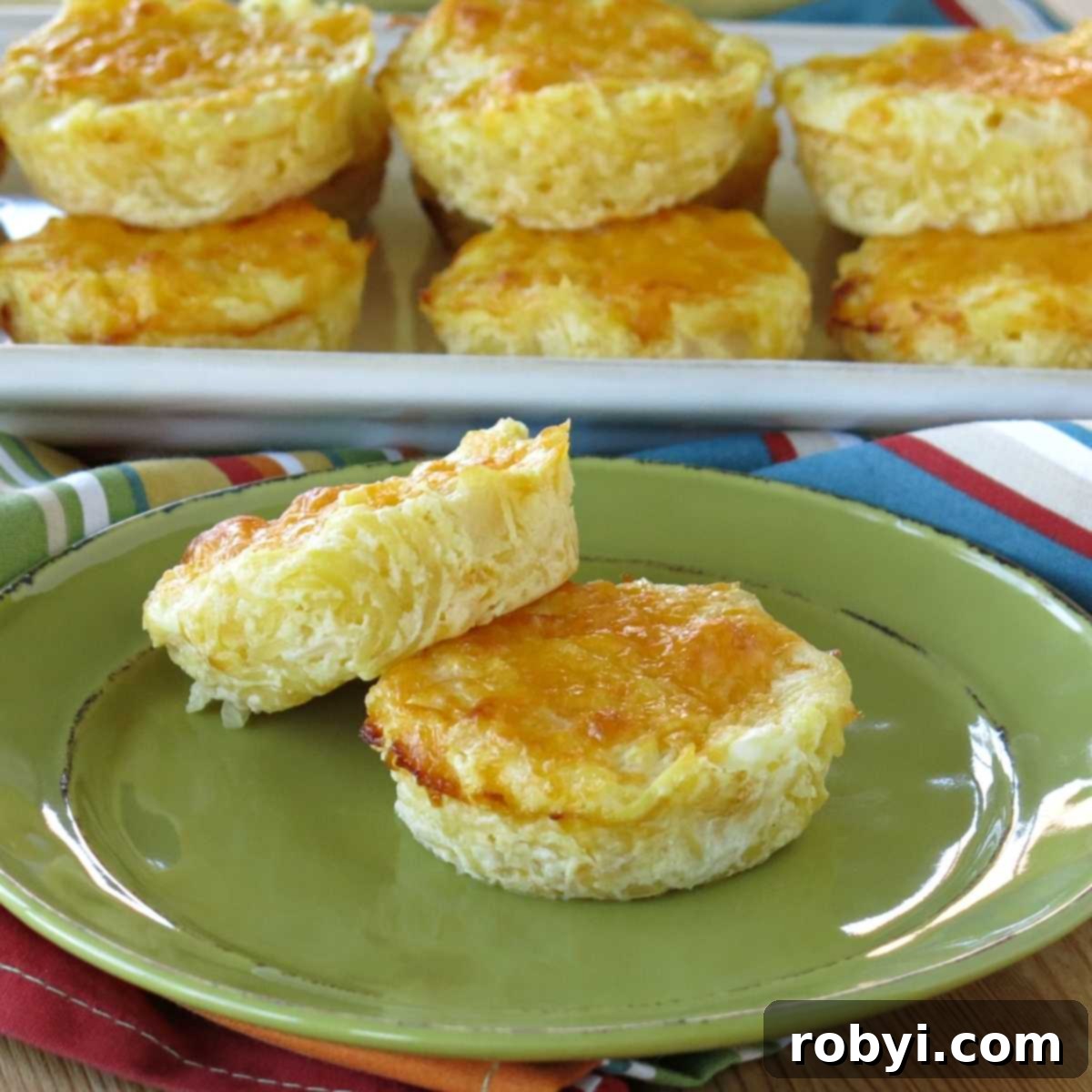 Two perfectly golden spaghetti squash au gratin mini casserole cups, ready for serving, with a platter of more in the background.