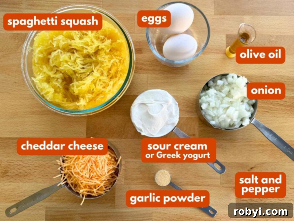 Fresh spaghetti squash, eggs, shredded cheddar cheese, a bowl of sour cream, a diced onion, olive oil, and garlic powder arranged on a wooden board, ready for cooking.
