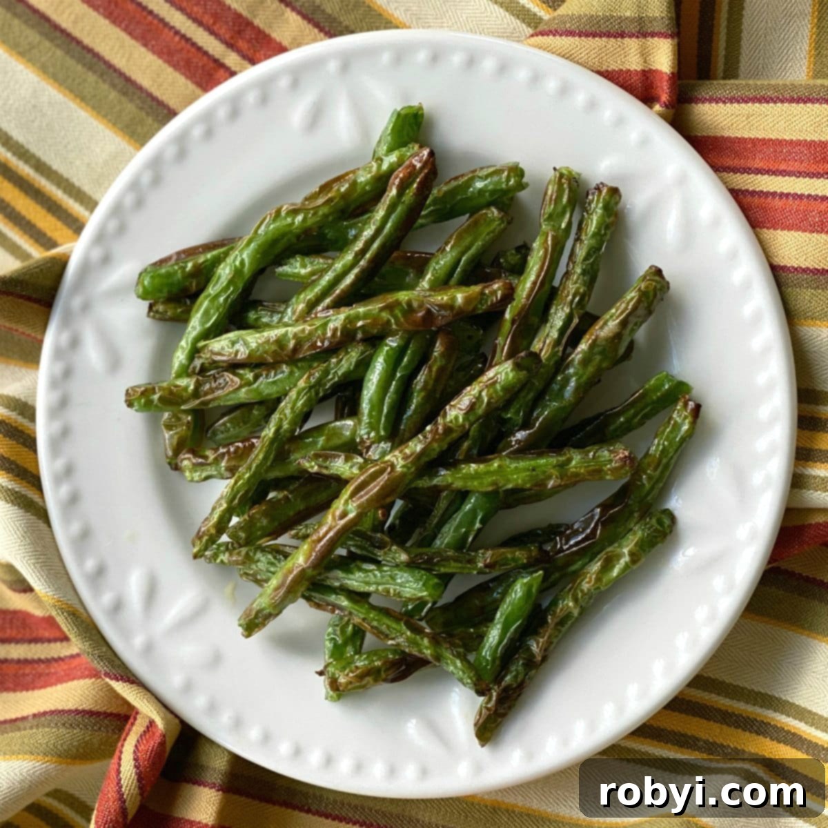 Crispy Roasted Green Beans beautifully arranged on a white plate, showcasing their inviting texture.