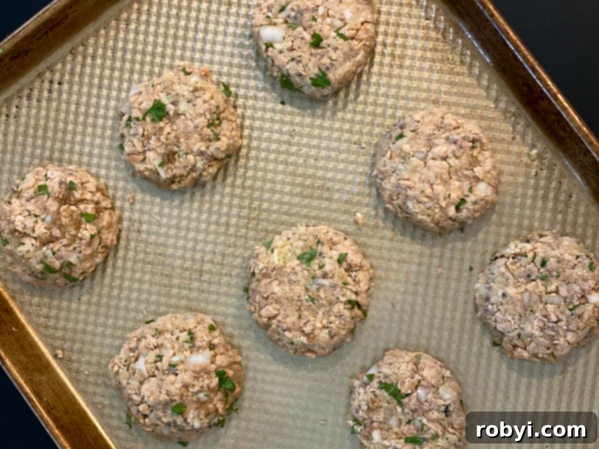 Baked Salmon Cakes: Two Ways (Patties or Muffin Tin) 3 A baking sheet filled with perfectly formed, uncooked salmon patties, ready for the oven. This image captures the simple preparation process.