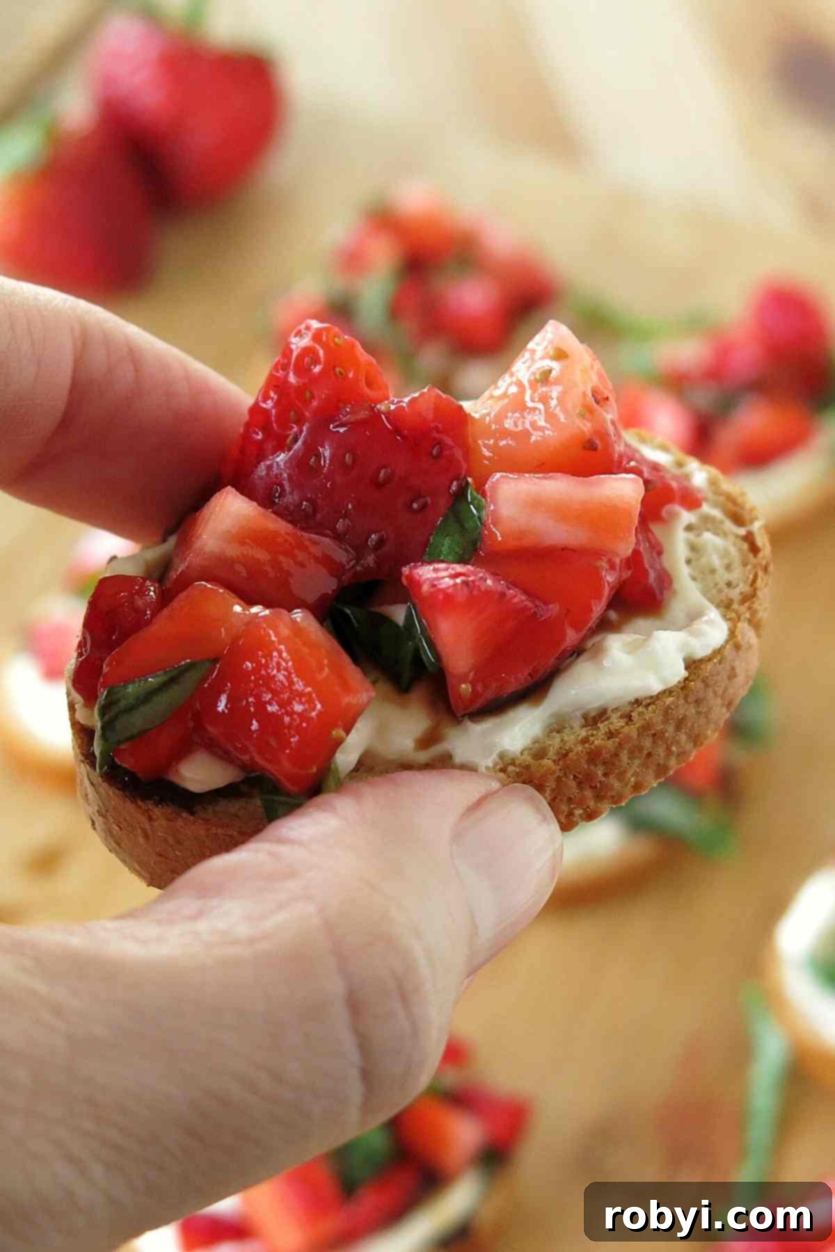 Fingers holding low-carb strawberry appetizer.