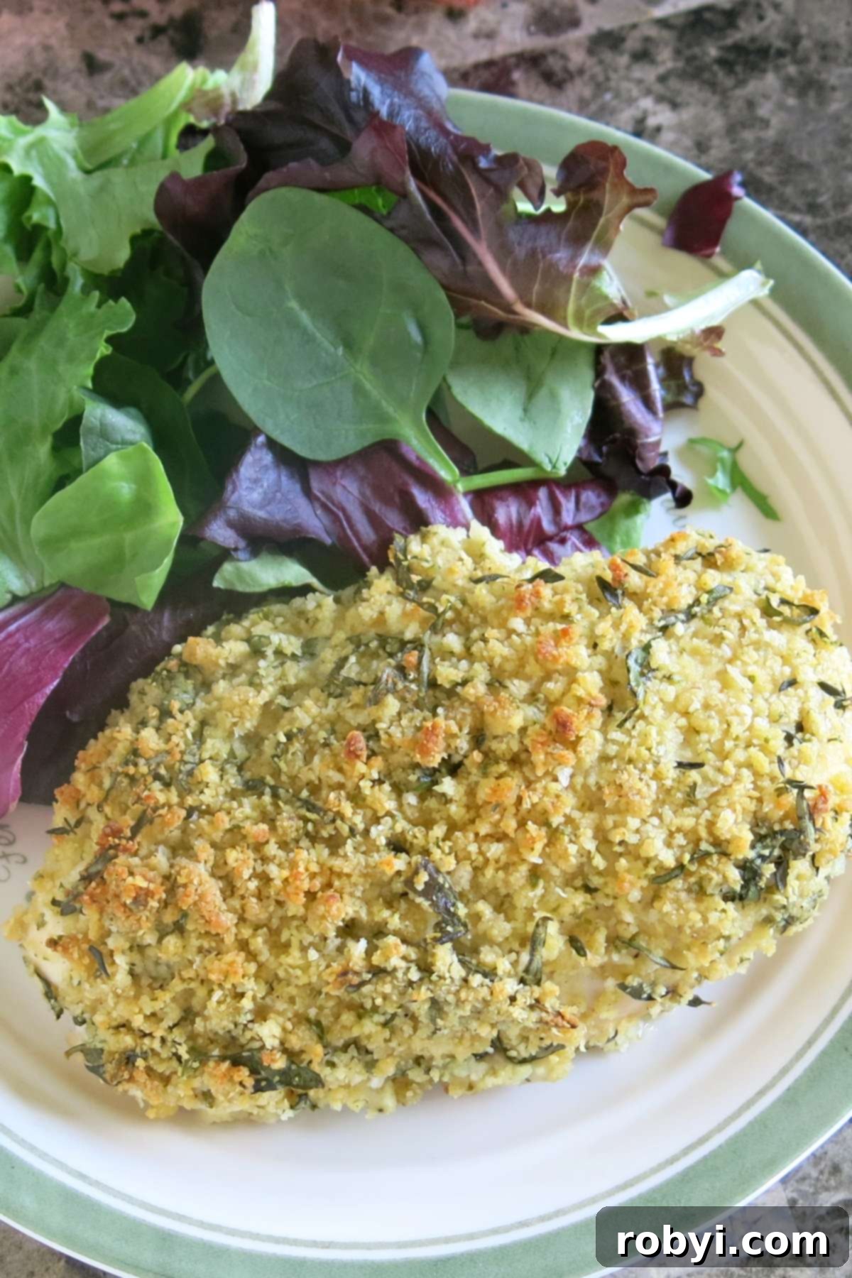 Close-up view of a perfectly golden-brown Parmesan and Herb Crusted Chicken on a plate.