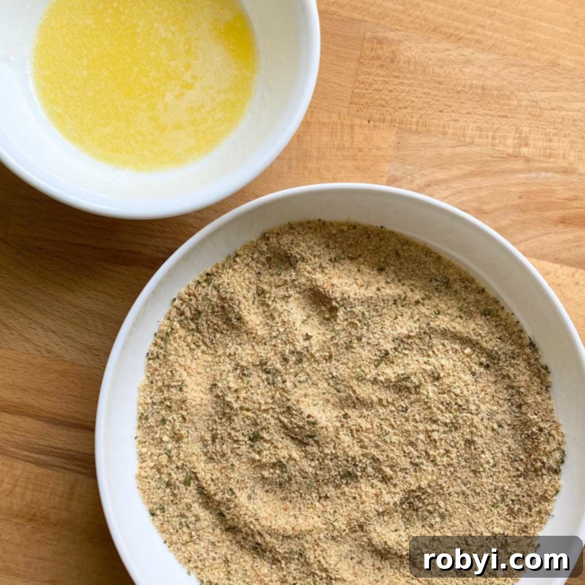 Melted butter in a small bowl and a shallow plate with parmesan breading.