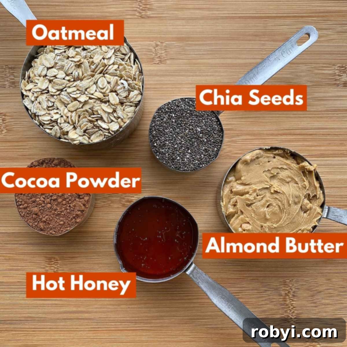 Five essential ingredients for Chocolate Bliss Balls displayed in individual measuring cups: old-fashioned oatmeal, unsweetened cocoa powder, chia seeds, creamy almond butter, and a rich golden hot honey.