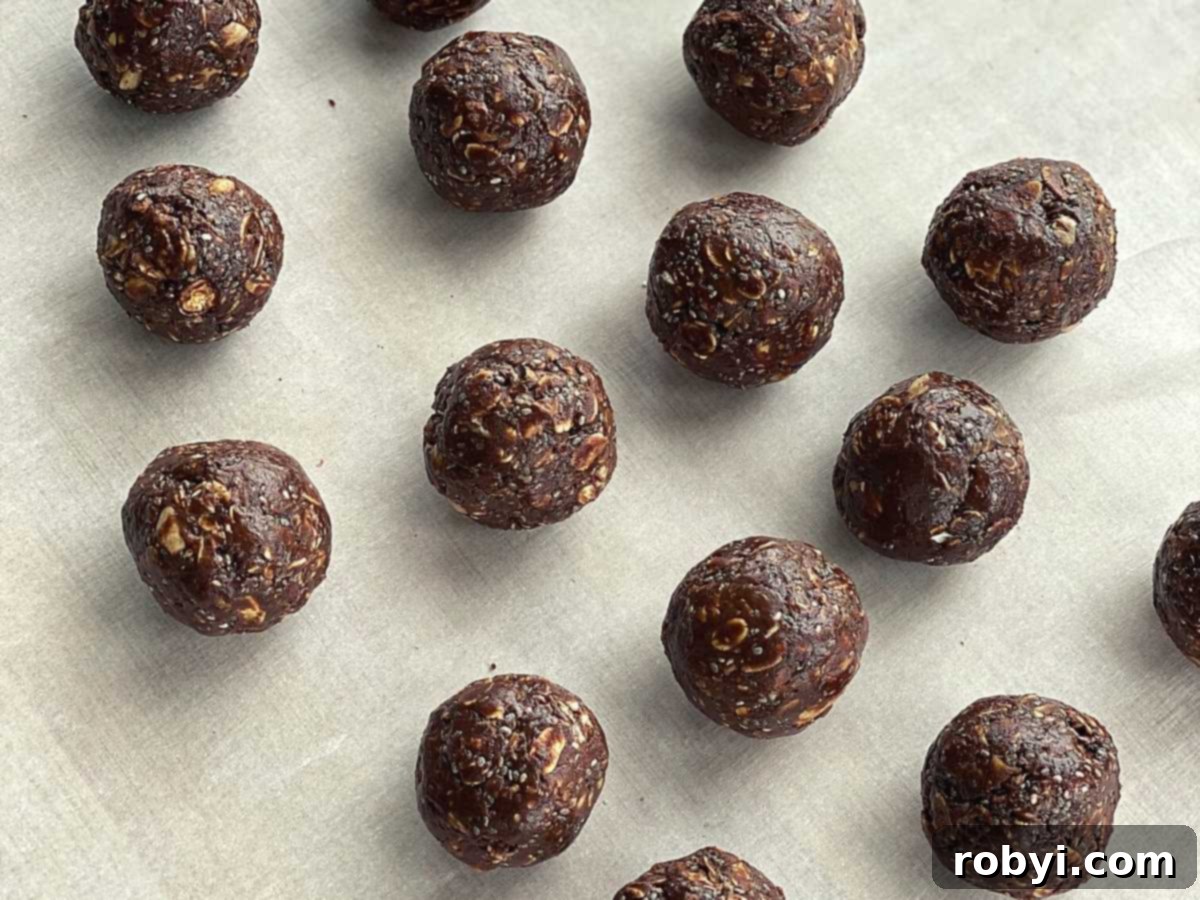Rows of perfectly formed hot honey chocolate bliss balls neatly arranged on parchment paper, ready for chilling or serving.