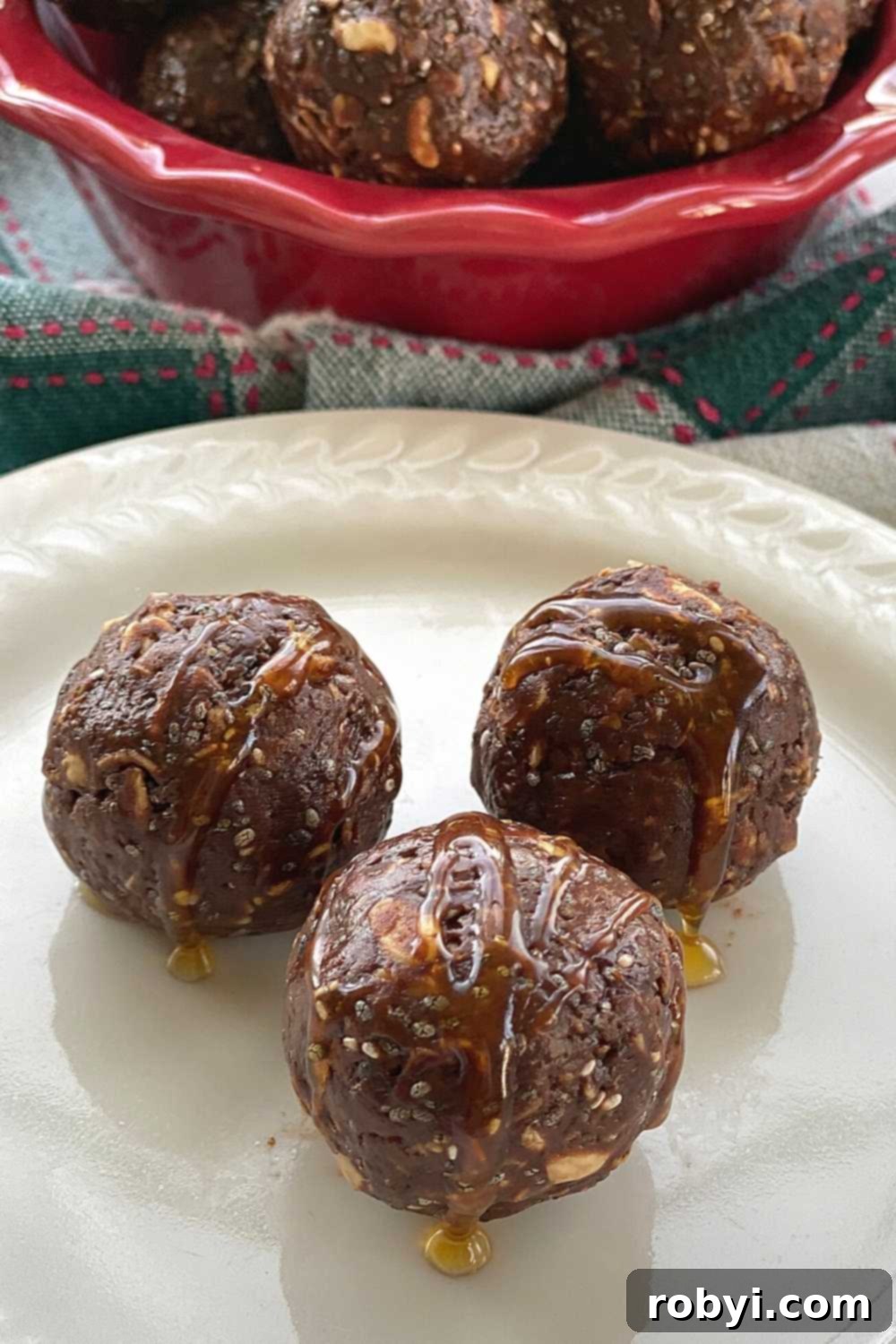 Three decadent chocolate bliss balls artfully arranged on a plate, elegantly drizzled with extra hot honey for an enhanced sweet and spicy experience.