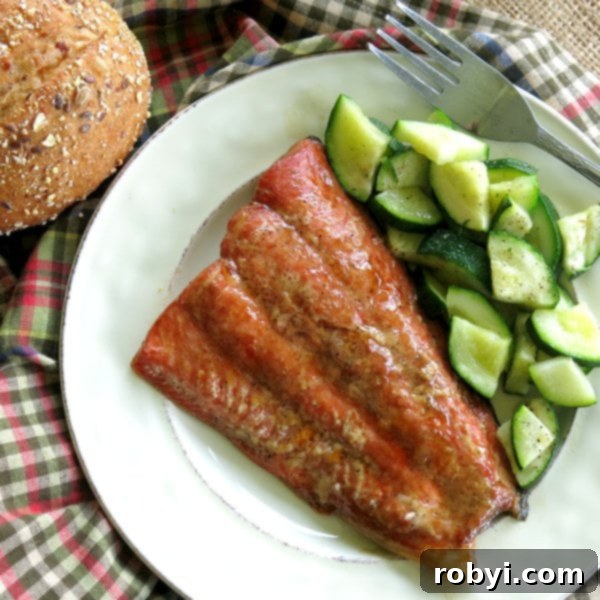 Exquisite Bourbon Marinated Salmon fillets served with roasted zucchini on a white plate, garnished with fresh herbs.