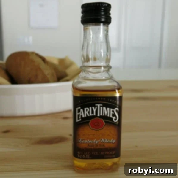 Small, inexpensive bottle of Kentucky bourbon whiskey on a rustic wooden table, ready for cooking.