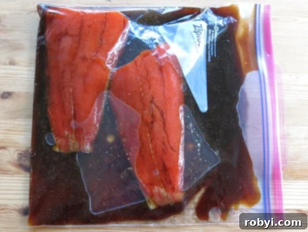 Fresh sockeye salmon fillets soaking in a rich, amber bourbon marinade within a resealable plastic bag.