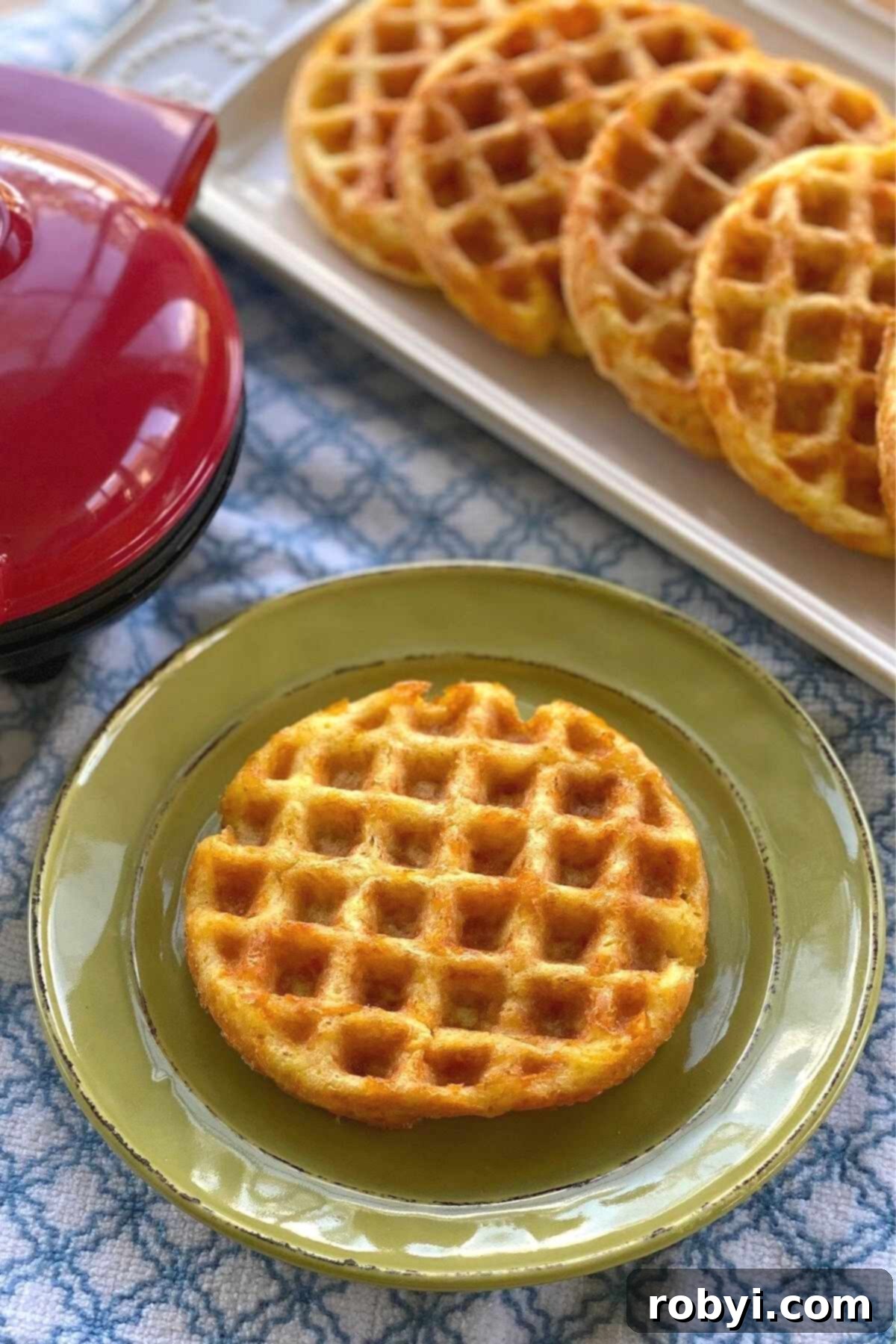 Basic keto chaffle on plate with more on platter behind it.