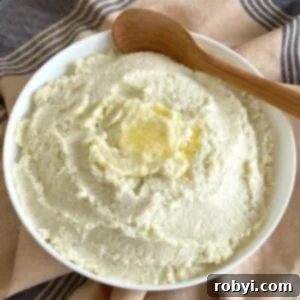 Frozen cauliflower mash in serving bowl with wooden spoon.