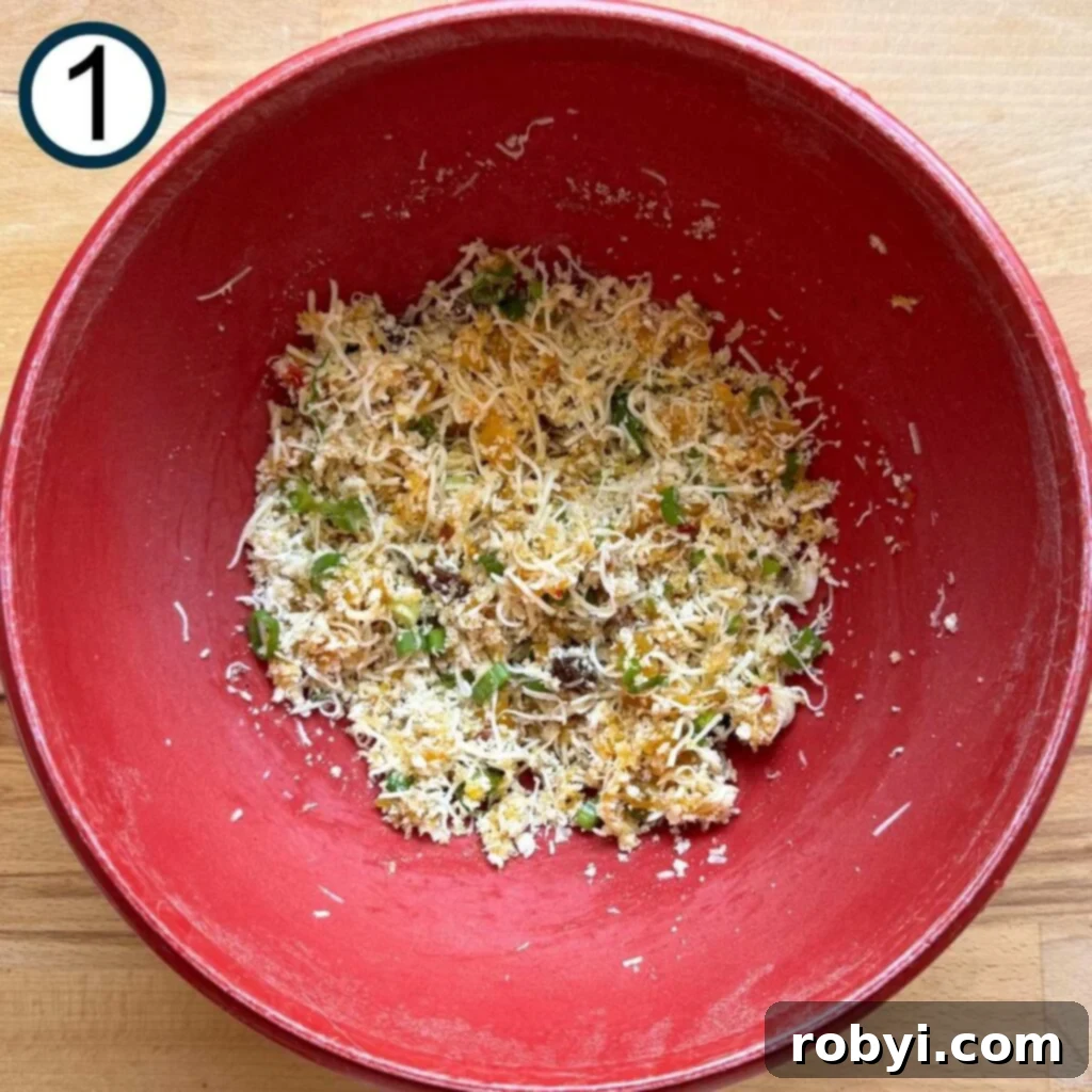 Red bowl with a mixture of panko bread crumbs, shredded mozzarella cheese, sliced green onion, mango chutney, salt, and pepper.