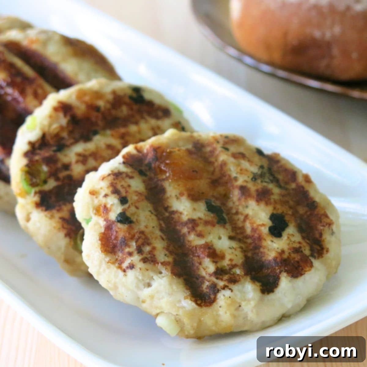 Grilled turkey burgers with mango chutney on a rectangle plate.