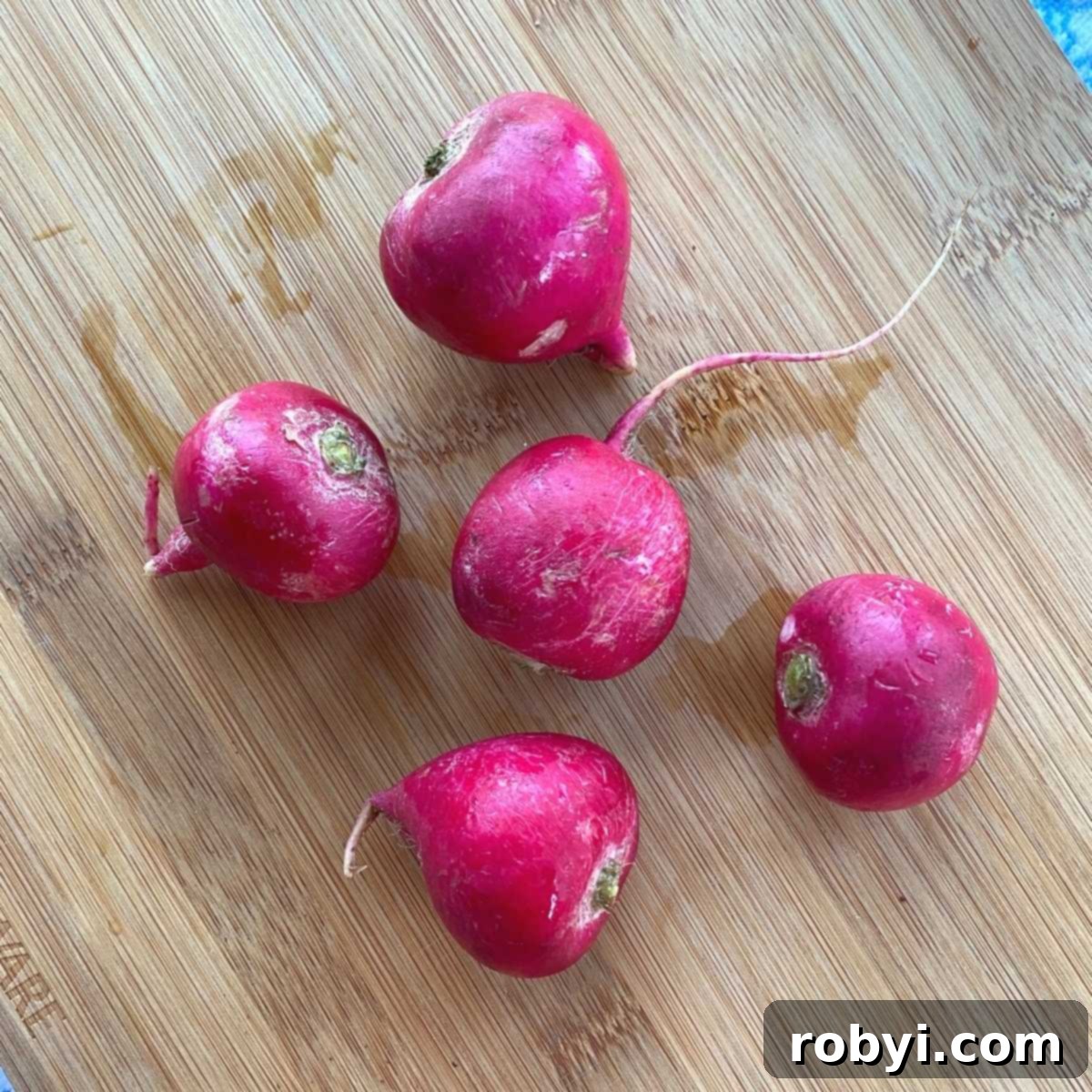 5 Red globe radishes on a cutting board.