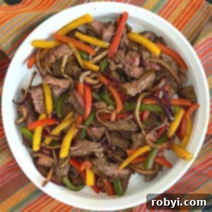 Air fryer steak fajitas with bell peppers and onion in a serving dish.