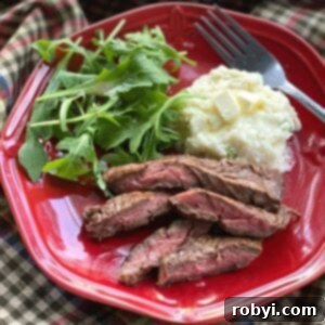 Slices of bavette steak on a plate with mashed cauliflower and arugula.