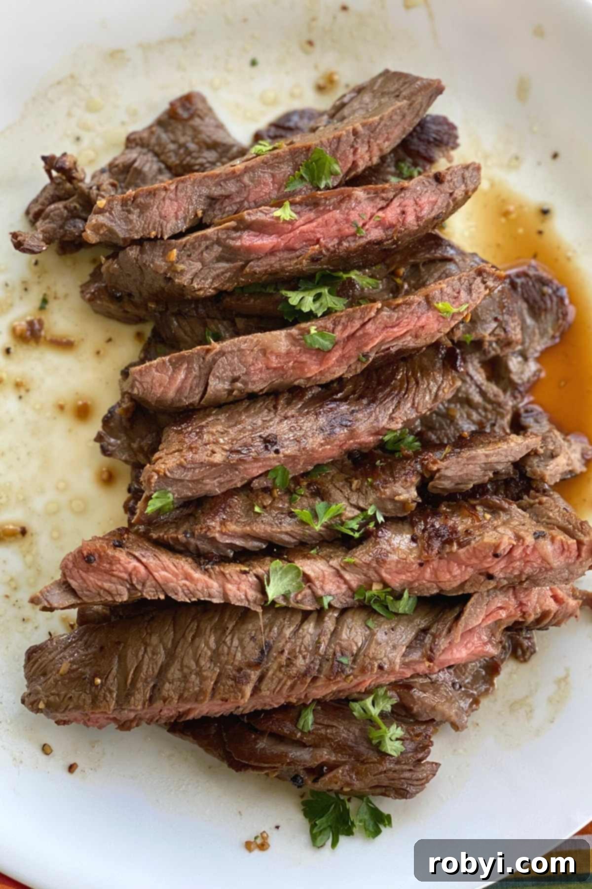 Slices of steak bavette piled on a plate and topped with parsley.