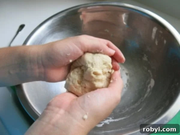 Hands kneading pretzel bites dough over a bowl.