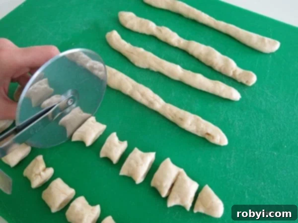 Pizza cutter cutting pretzel dough into bite sized pieces