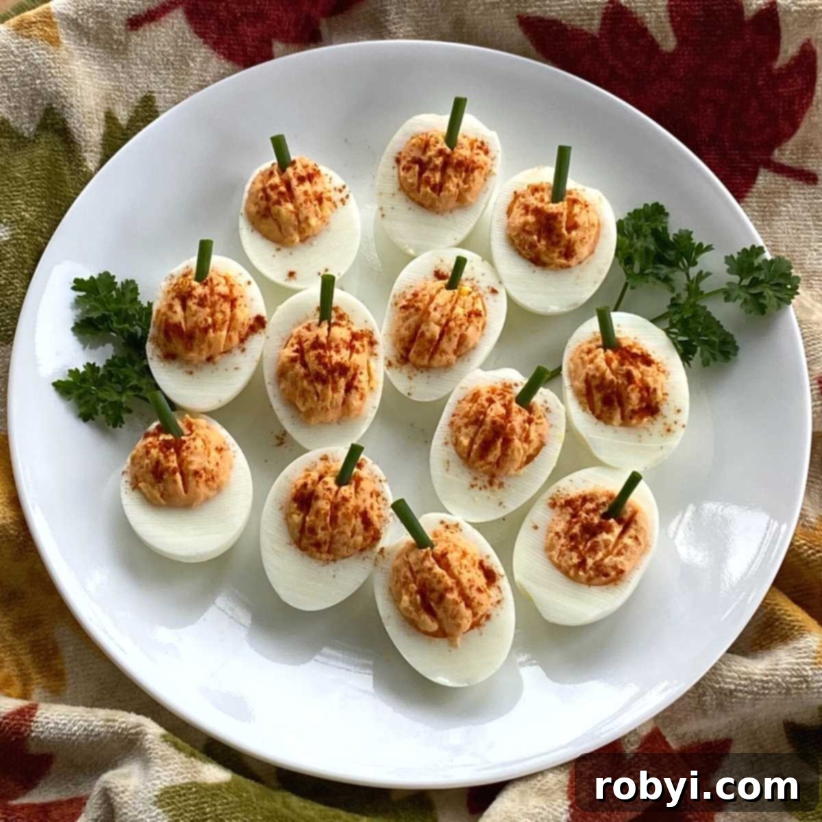 Twelve deviled egg pumpkins arranged artfully on a plate.