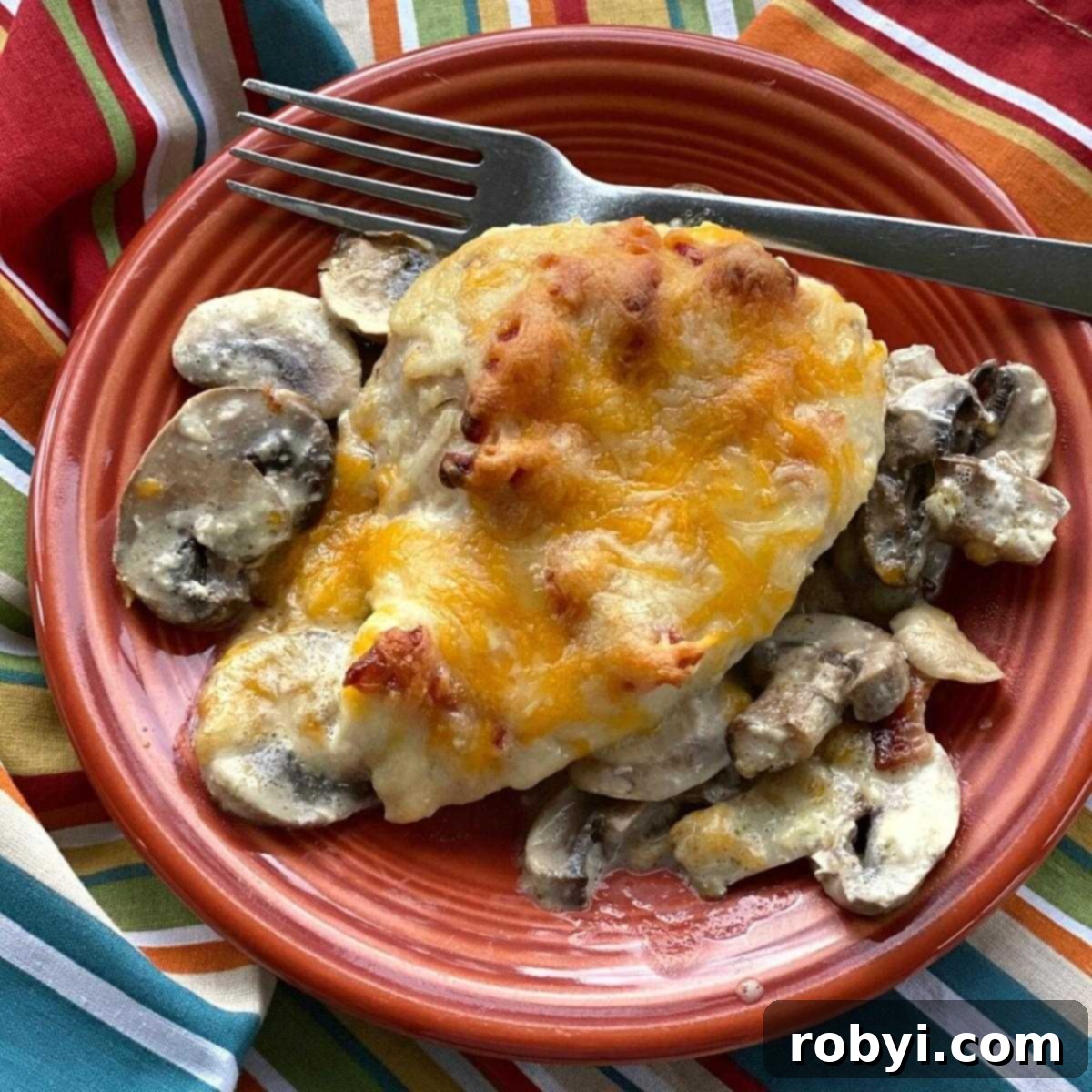 Alice Springs Chicken topped with generous honey mustard and melted cheese, served on a plate with sautéed mushrooms.
