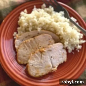 Three slices of turkey tenderloin on a plate with cauliflower rice and a fork.