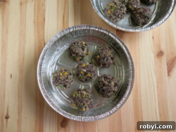Uncooked black bean cakes neatly arranged in a baking tin, ready for chilling or freezing
