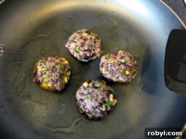 Golden-brown vegan black bean cakes sizzling in a frying pan