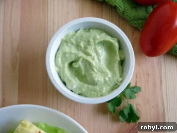 A vibrant green avocado cream sauce in a small serving cup