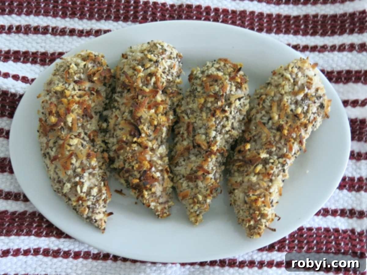 Four crispy baked chicken fingers in a row on a plate.