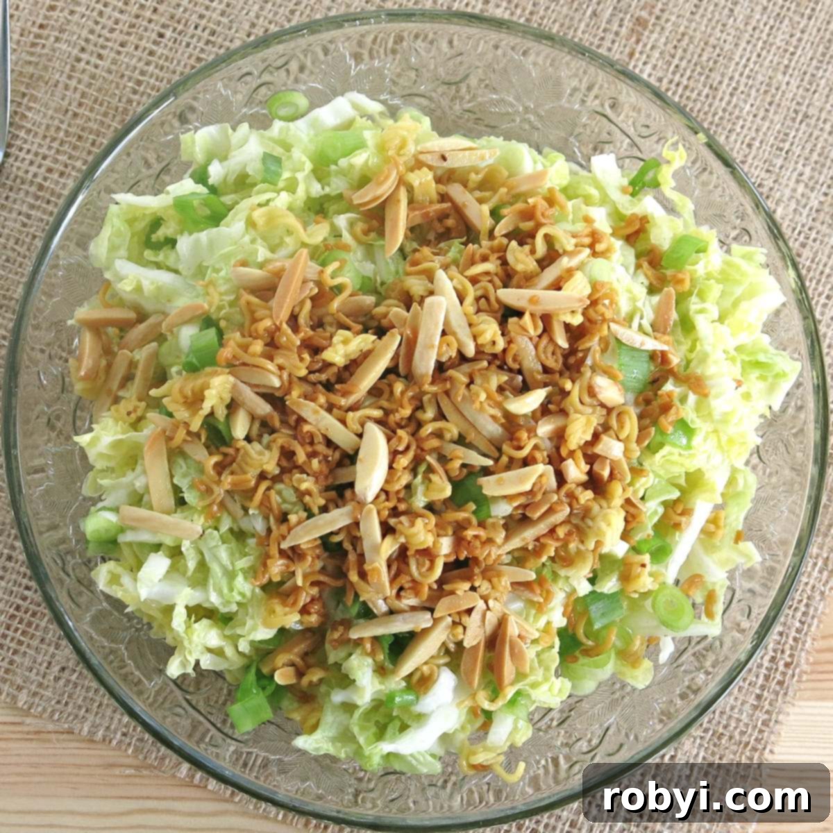A glass salad bowl filled with refreshing ramen noodle cabbage salad.