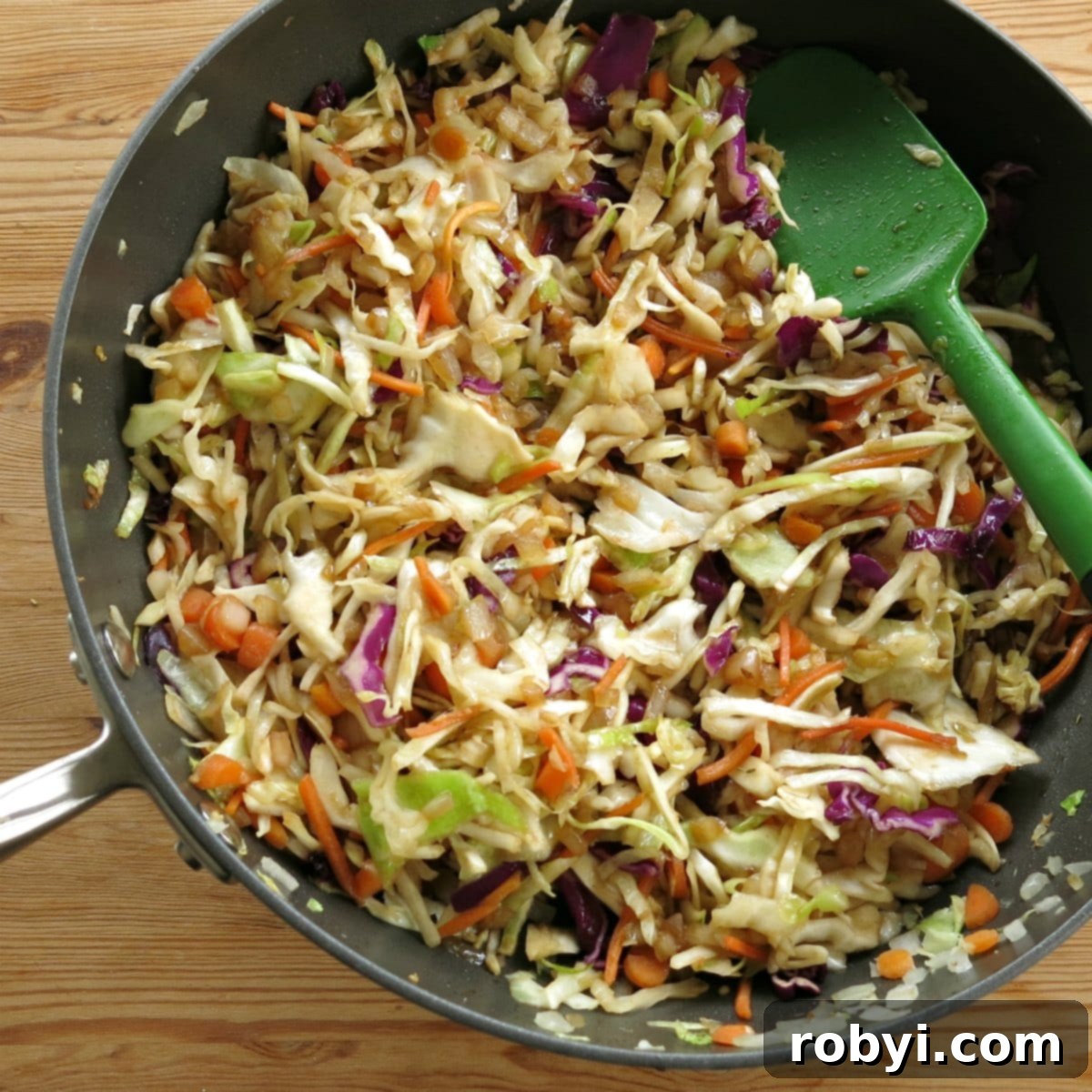 A pan with cooked egg roll vegetables and a serving spoon, ready to be enjoyed.