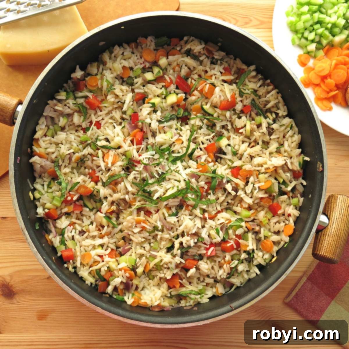 Vegetable rice pilaf in a skillet, with fresh carrots and celery beside it.