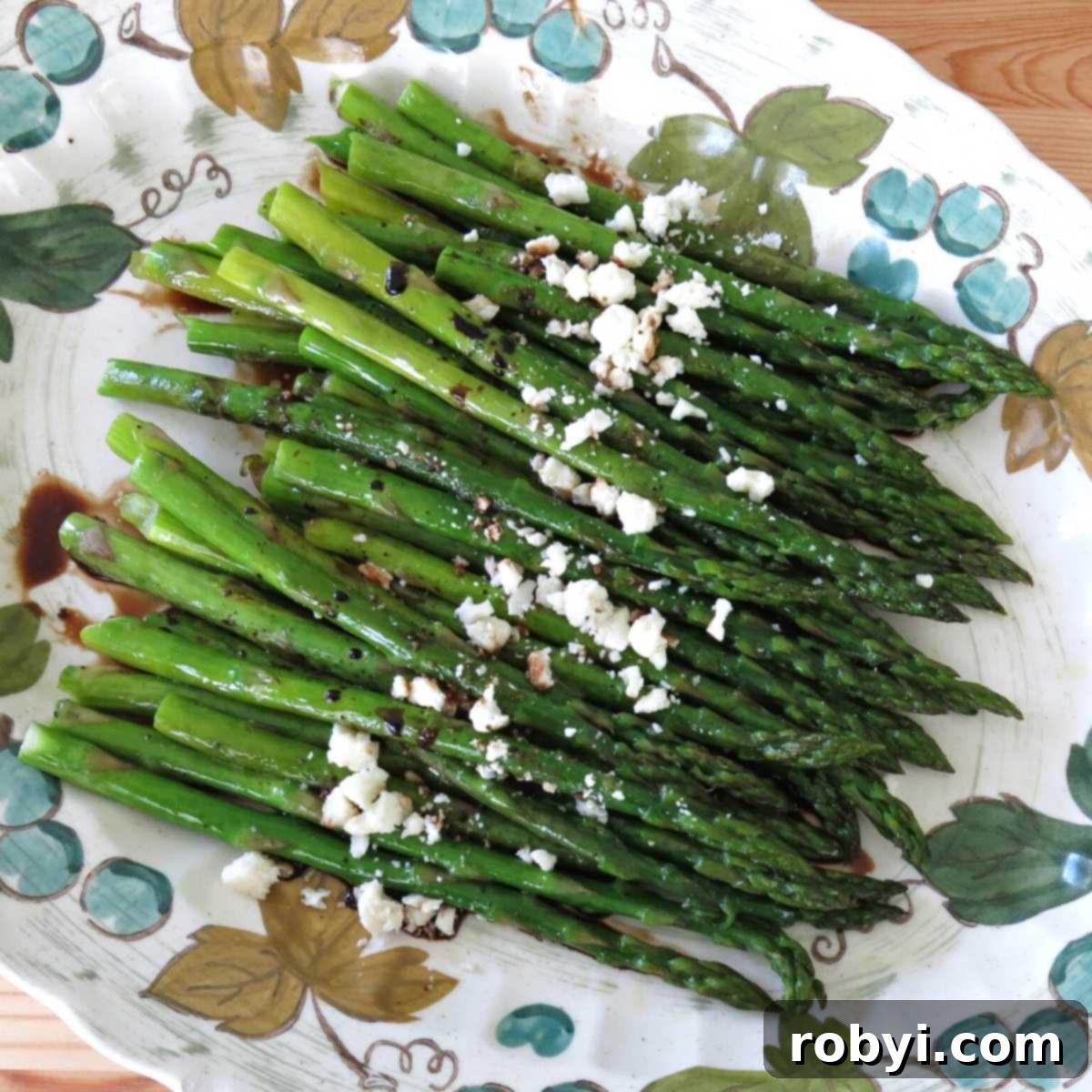 Elegantly roasted asparagus with balsamic glaze and feta cheese, served on a white platter.