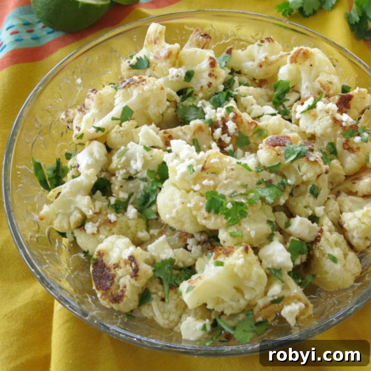 A glass bowl filled with Mexican Street Style Cauliflower, garnished and ready to serve.