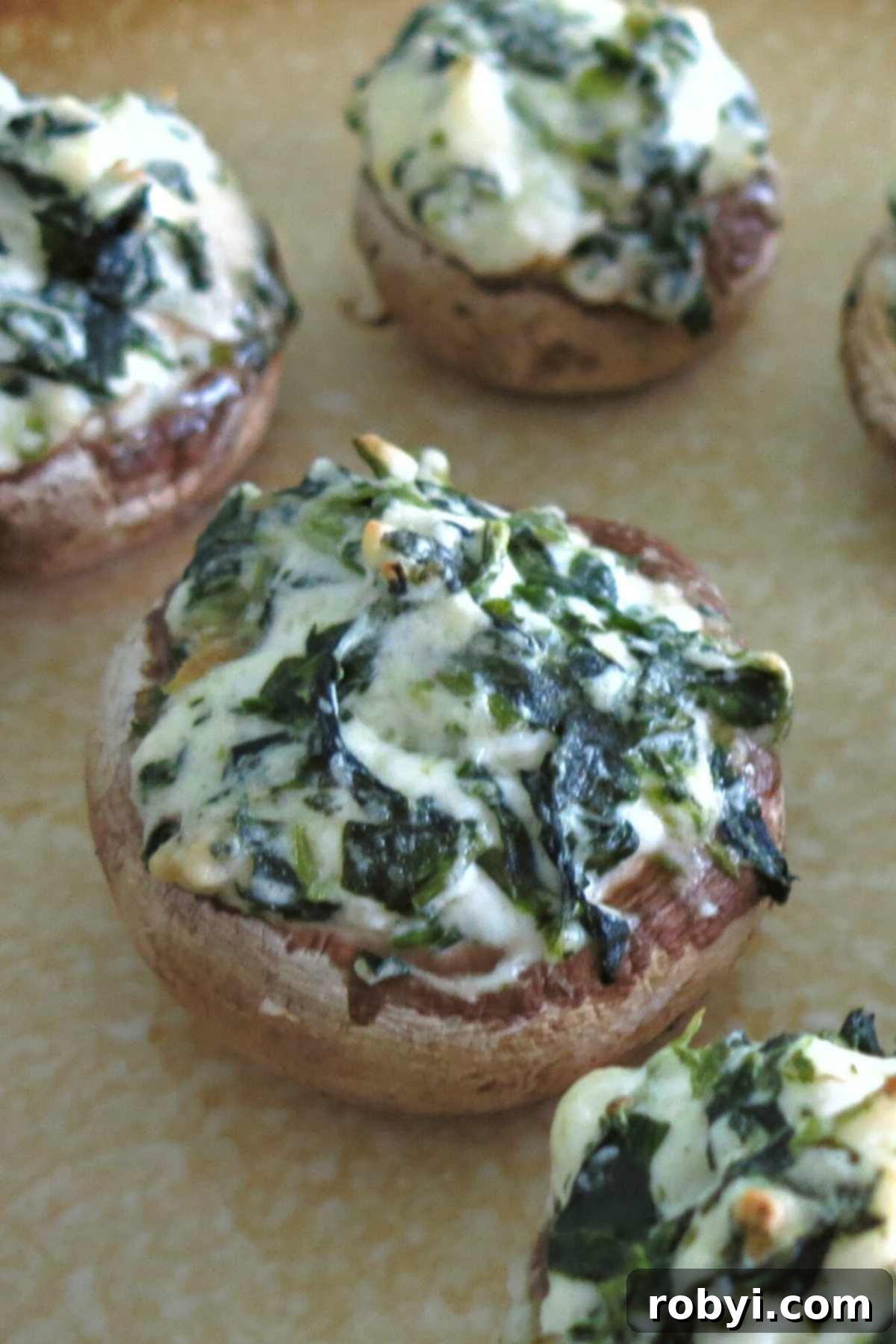 A beautifully presented platter of cooked stuffed mushrooms with cream cheese and spinach, garnished and ready to serve.