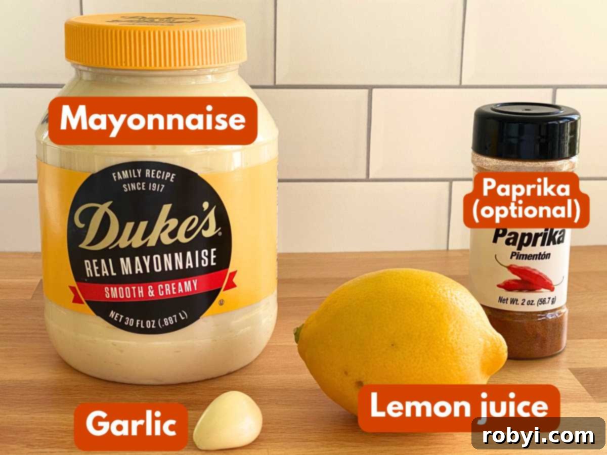 Homemade Lemon Garlic Aioli: Simple & Delicious 3 Essential ingredients for lemon garlic aioli laid out: a jar of creamy mayonnaise, a whole lemon, several cloves of fresh garlic, and a small dish of paprika (labeled as optional). The focus is on freshness and quality.