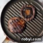 Two balsamic portobello mushrooms on a grill pan.