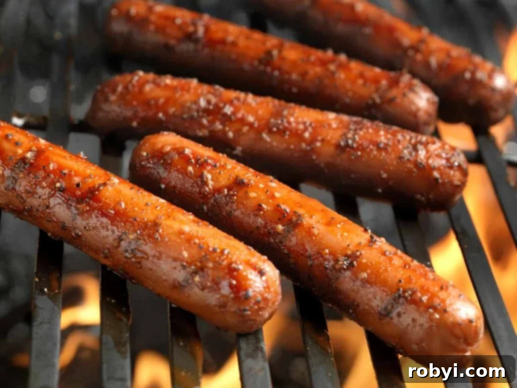 Five grilled hot dogs on a grill grate.